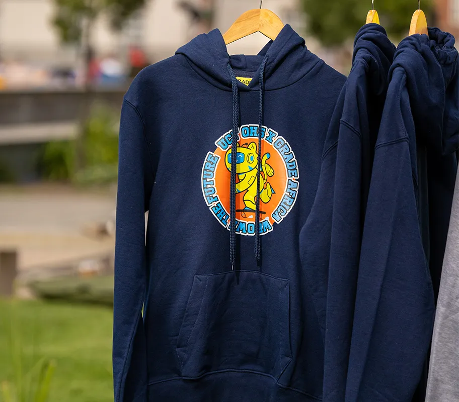 Navy UCT OHS x Grade Africa hoodie with a yellow robotic tiger mascot print, hanging on a rail