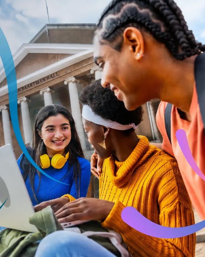 Three young adults laughing together over a laptop outside a university building