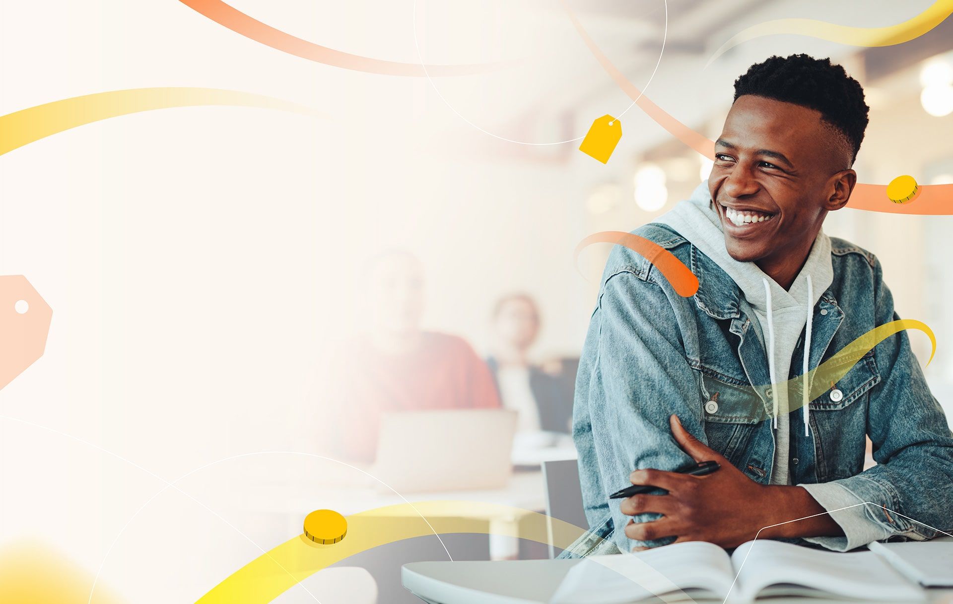 A smiling learner in a denim jacket sitting at a desk with an open textbook