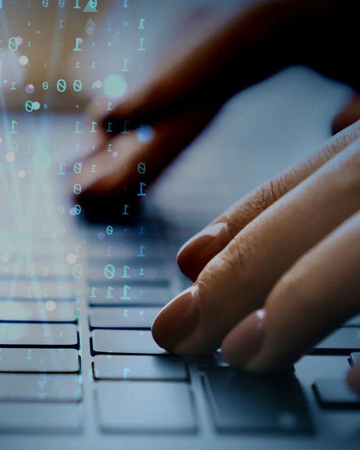 Hands typing on a laptop keyboard, with lines of code overlaid