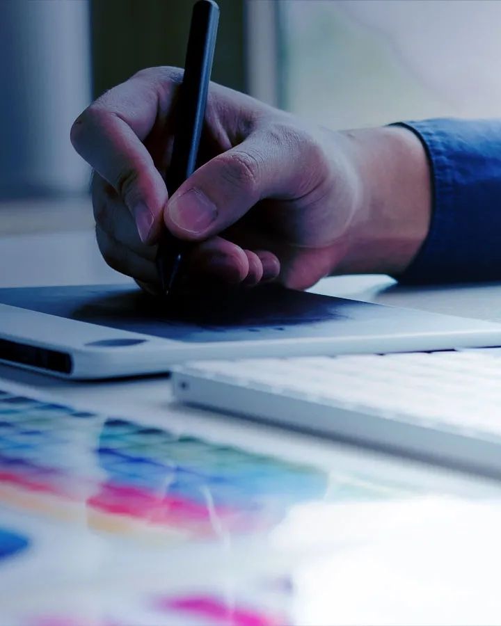 A designer drawing on a graphics tablet beside colour swatches