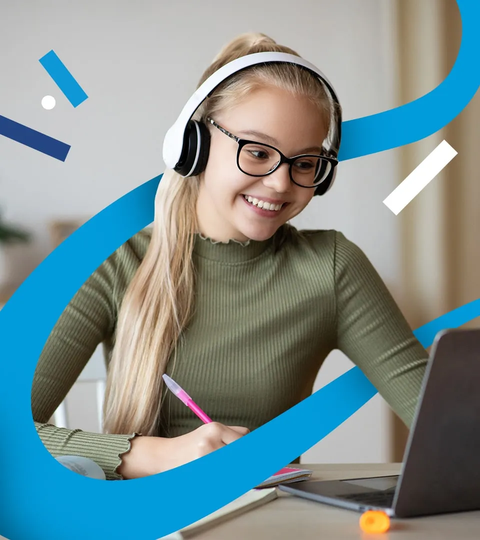 A learner wearing headphones smiles at her laptop while taking notes