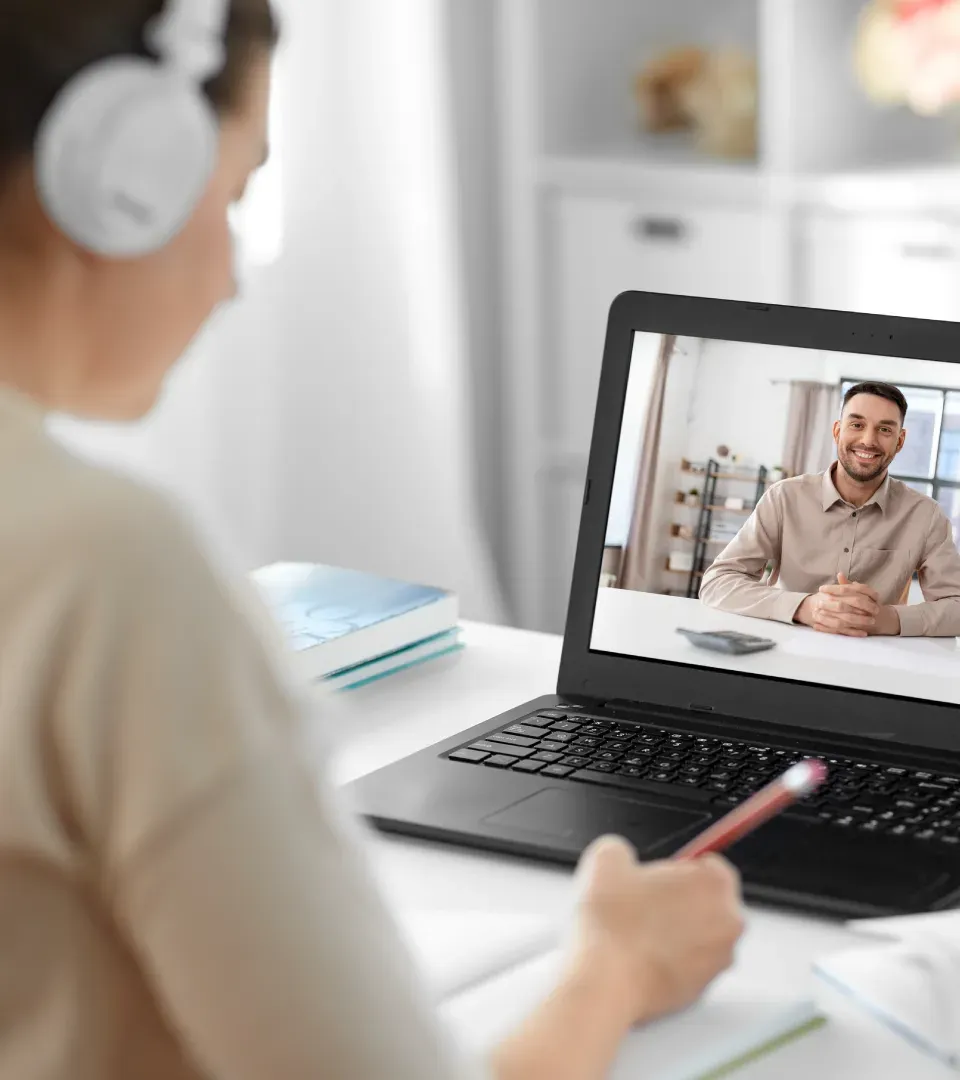 A learner wearing headphones in a video call with a facilitator
