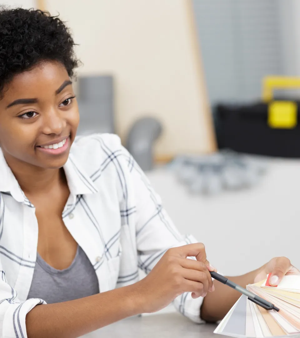 A designer smiling while choosing colours from a swatch book